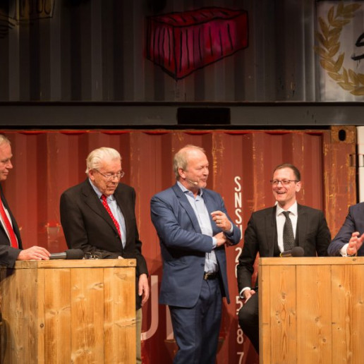 BLG Logistics Jubiläum: Auf der Bühne stehen 5 Männer an Holzstehtischen un halten eine Podiumsdiskusion