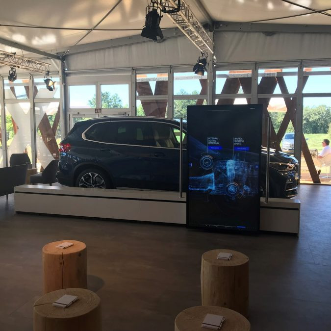 BMW Group: Im inneren des Zeltest steht ein BMW X5, auf einem Display vor dem Auto wird das Getriebe erklärt.