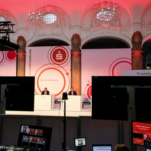Die Sparkasse Bremen Mitgliederversammlung: Blick aus der Technik, zwischen zwei Bildschirmen, auf die Bühne.