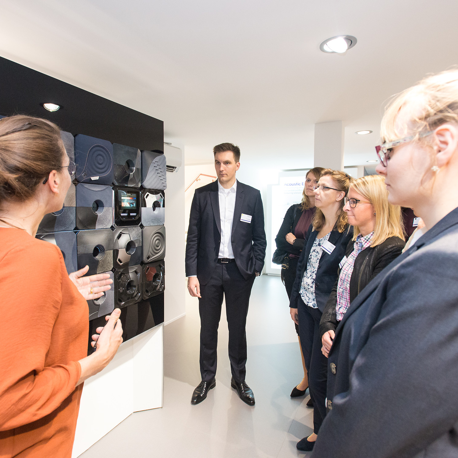 Faurecia Messe: Sechs Personen Stehen auf dem Messestand vor einem Exponat und lassen es sich erklären.