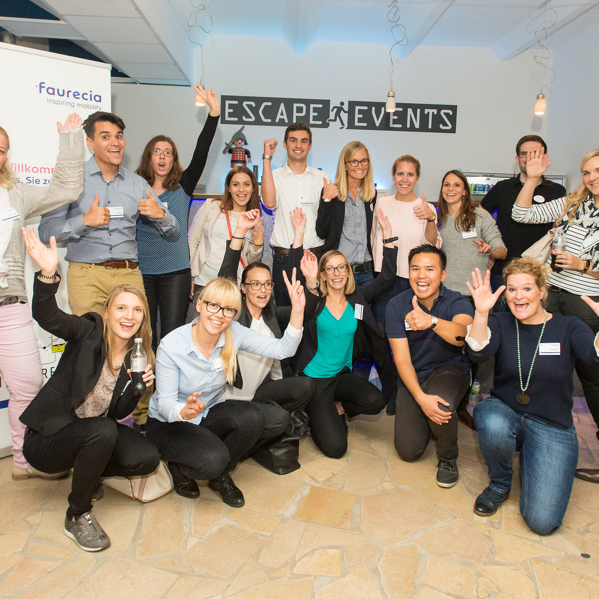 Faurecia Messe: Gruppenbild auf dem Messestand mit 18 Personen. Alles Lachen und Jubeln.