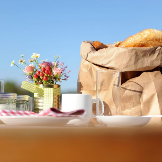 Göbber Mitarbeiterfrühstück: Eine gefüllte Brötchentüte auf einem eingedeckten Tisch im freien.