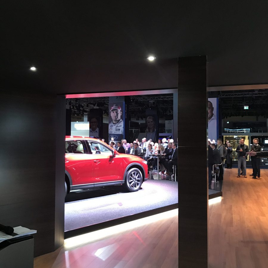 Mazda Messeaktivierung IAA: Blick aus dem Hintergrund auf den Messestand, auf dem ein roter Mazda steht.