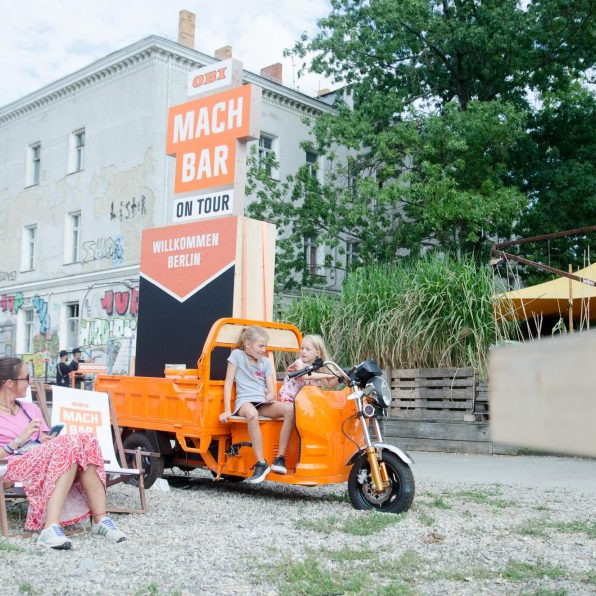 OBI MachBar Roadshow: zwei Kinder sitzen auf einem orangenen Motorrad.