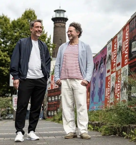 André Furtkamp und Kai Janssen stehen vor dem Leuchtturm Heliosturm in Köln-Ehrenfeld.
